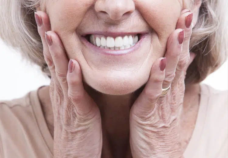 An older woman smiling as she touches her cheeks in excitement