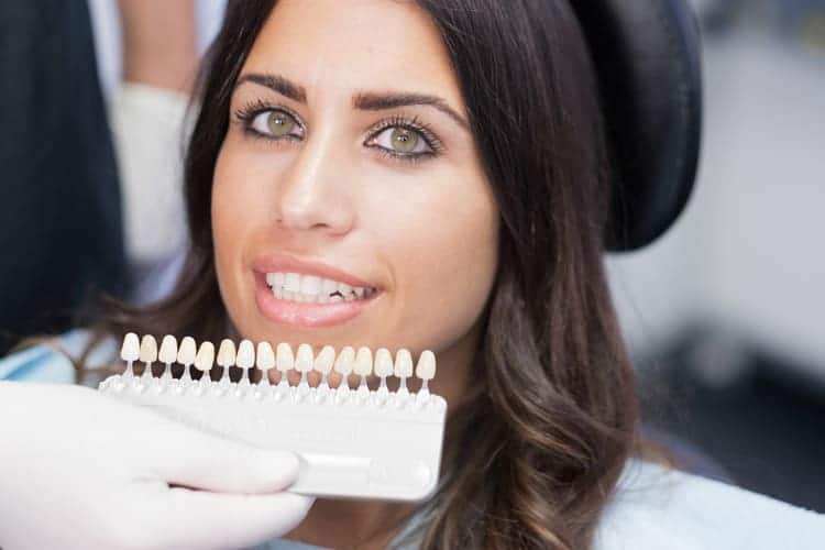 A woman checking with her dentist on what shade of veneers match the natural color of her teeth